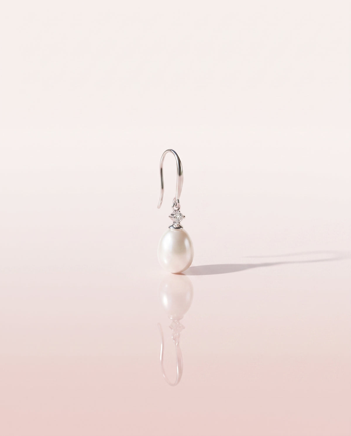 Freshwater pearl drop earring on a glossy pedestal with soft reflection