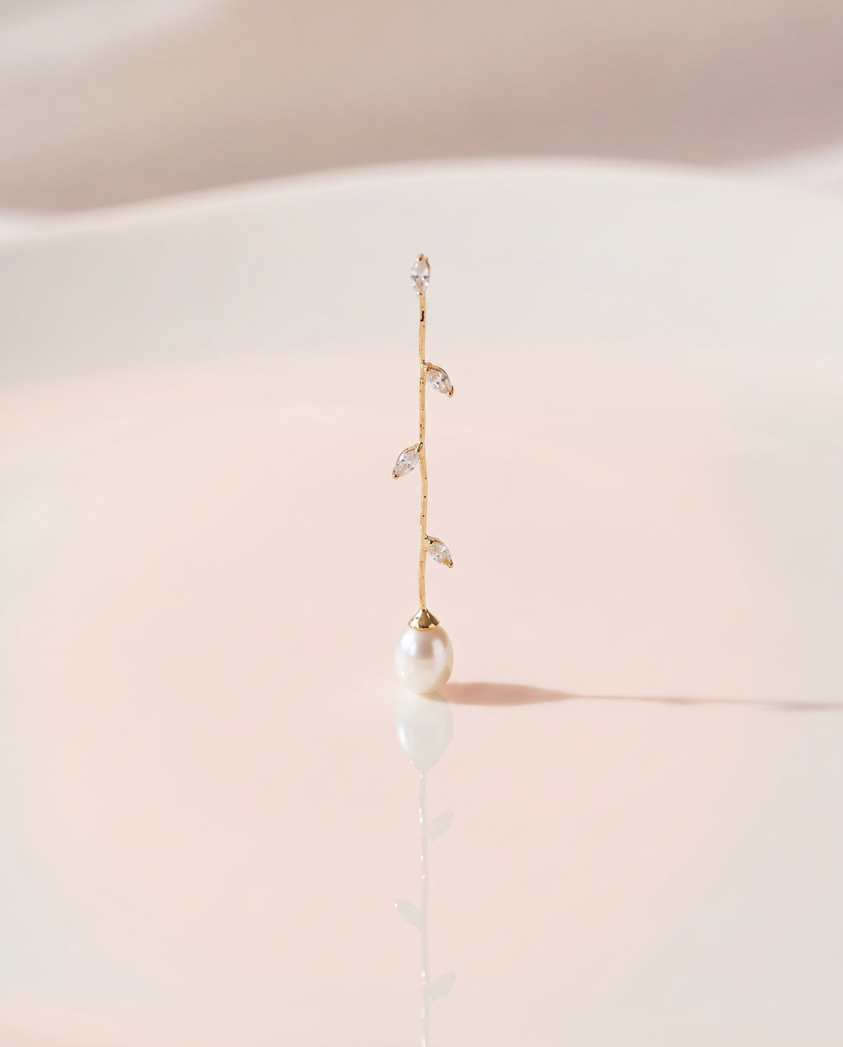 Gold Vine Pearl Drops freshwater pearl earring on a glossy pedestal with soft reflection