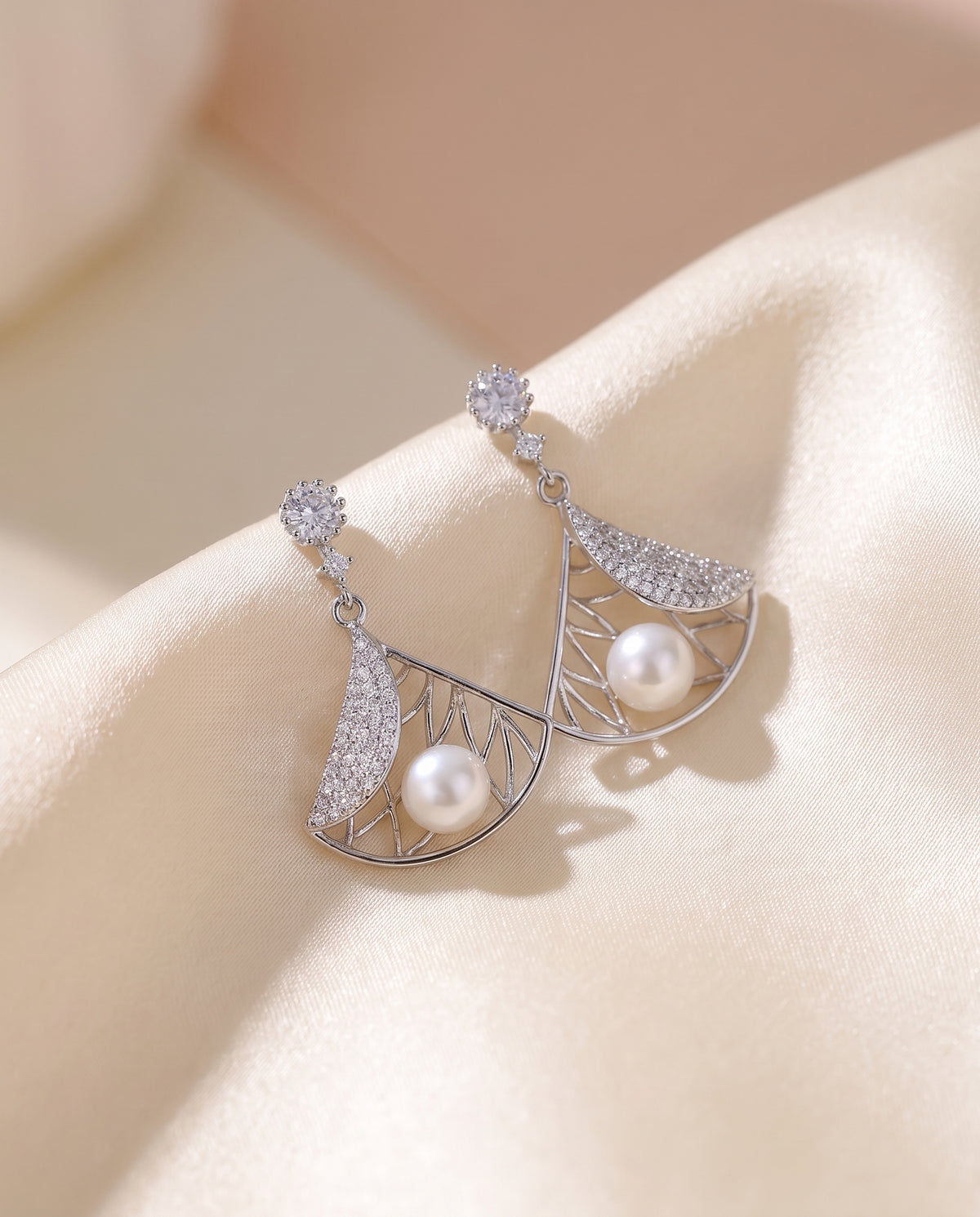 Deco Fan Pearl Drop Earrings draped on champagne silk