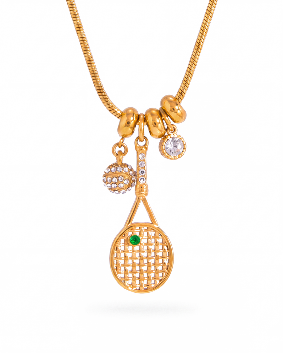 Gold tennis racquet charm necklace with pave ball and crystal on a snake chain, white background