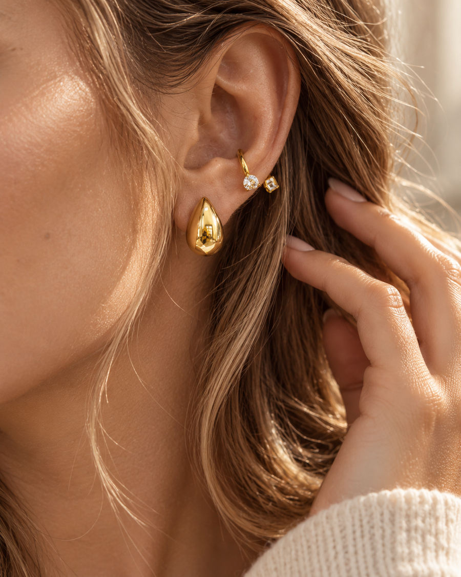 Teardrop huggie earrings worn with hair swept back, seamless polished gold drop on a hinged wire, waterproof 18k gold plated steel