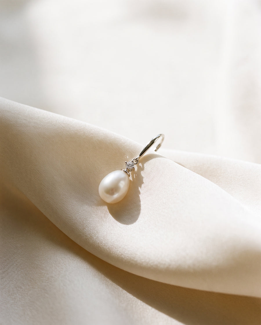 Freshwater pearl drop earring draped on champagne ivory silk