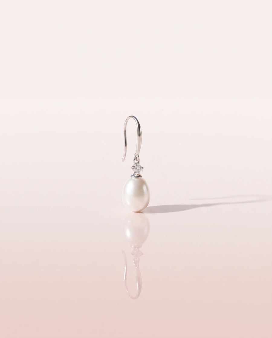 Freshwater pearl drop earring on a glossy pedestal with soft reflection