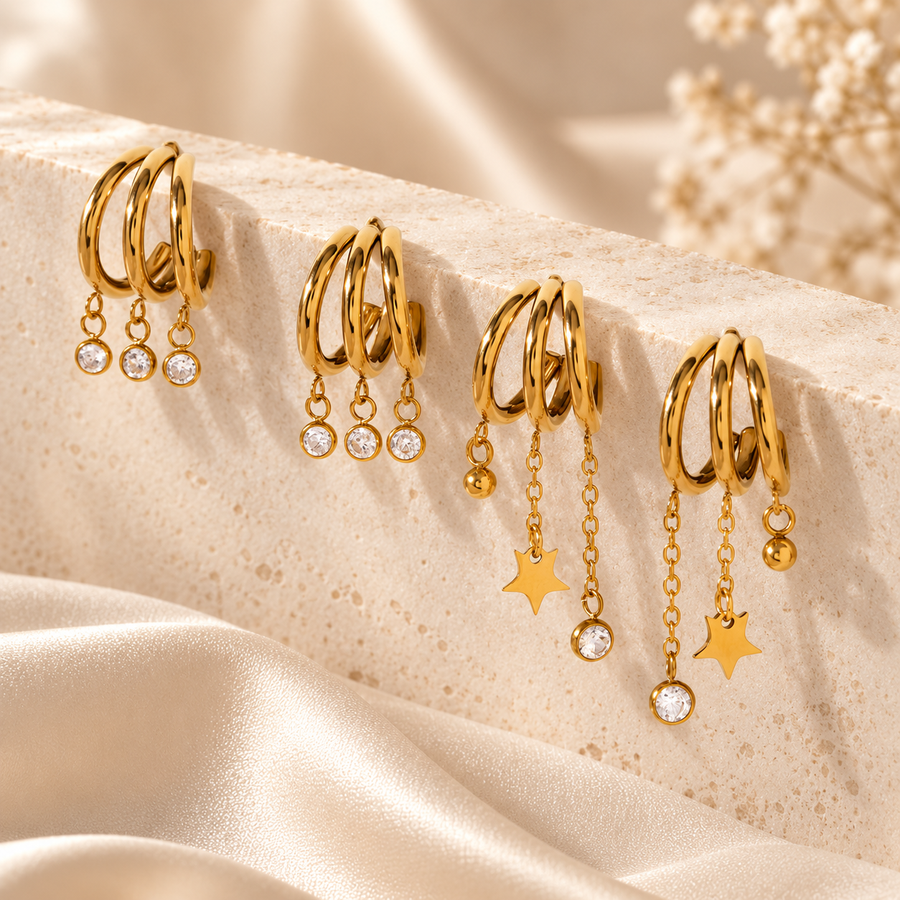 Triple hoop crystal drop earrings on cream silk, shown beside a companion pair with star drops, 18k gold plated stainless steel