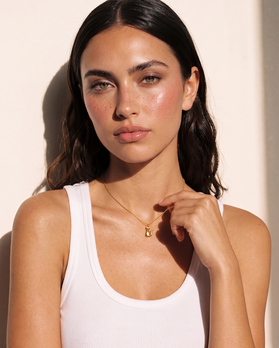 Model resting her fingertips on the chain beside the cat pendant