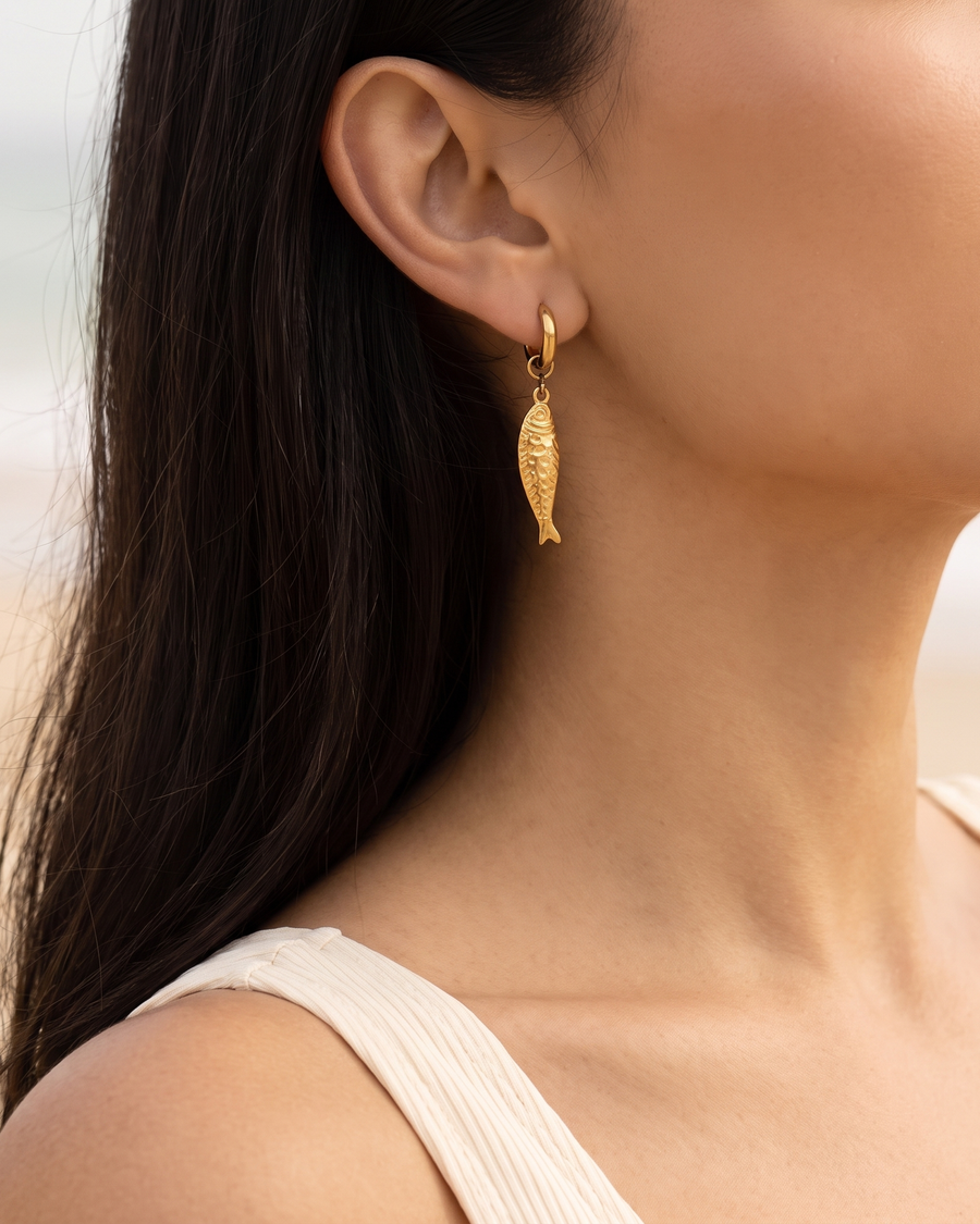 Gold fish drop huggie earring worn on the ear