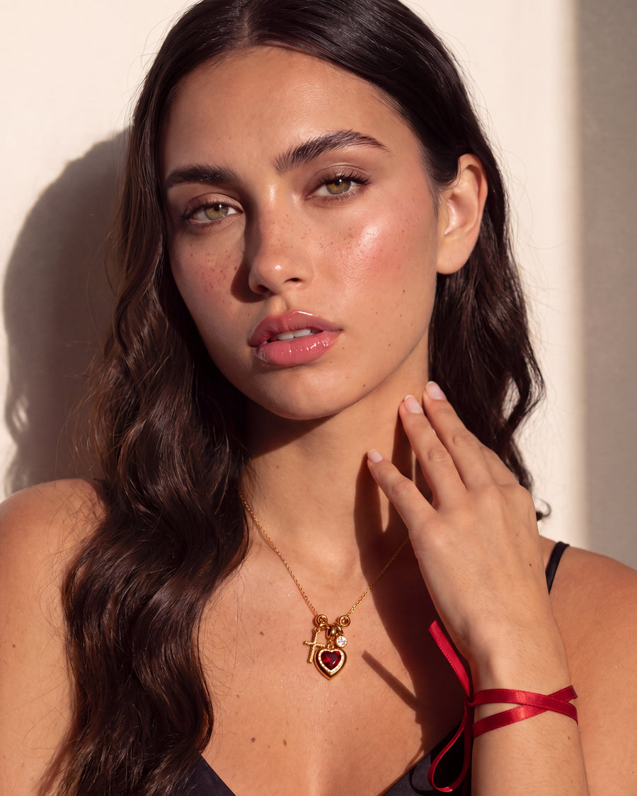 Model with a hand at her collarbone beside the fine chain of the necklace
