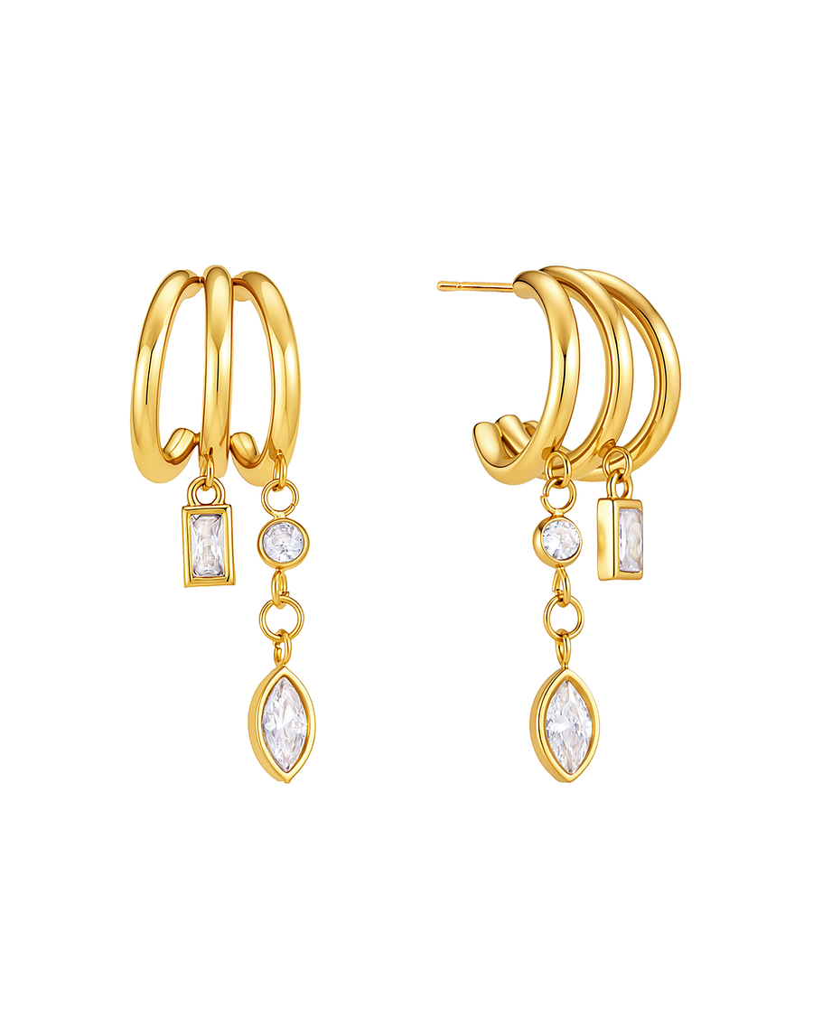Tassel hoop earrings on white — three fine gold half-hoops with two chains carrying a baguette, a round and a marquise crystal