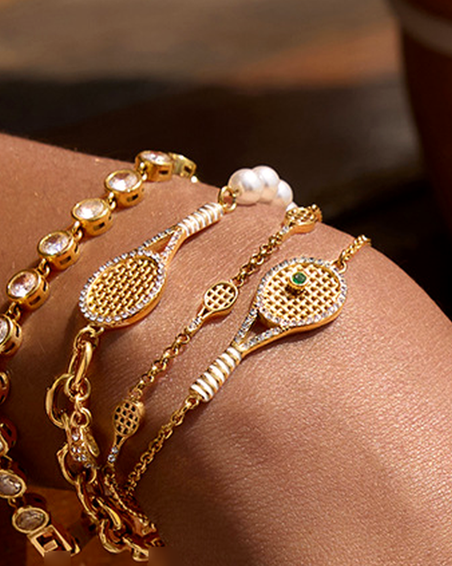 All four racquet bracelets stacked on a sunlit wrist