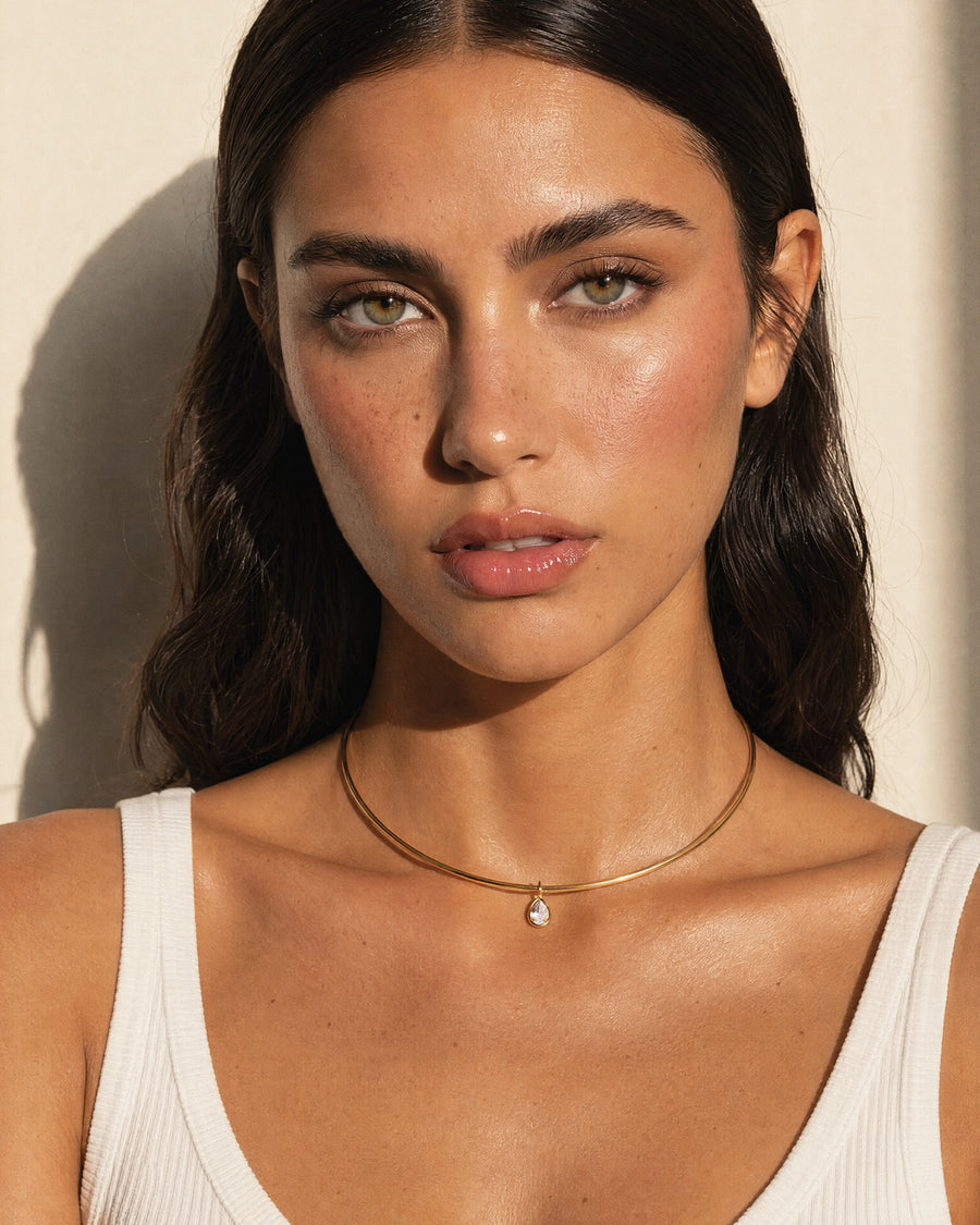 Model wearing the gold teardrop collar necklace at the base of the neck