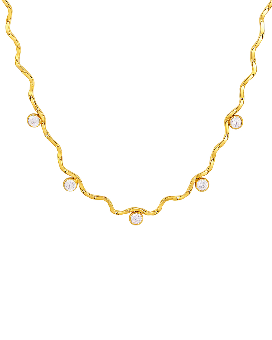 Gold wave chain necklace with five bezel-set clear stones, laid flat on white