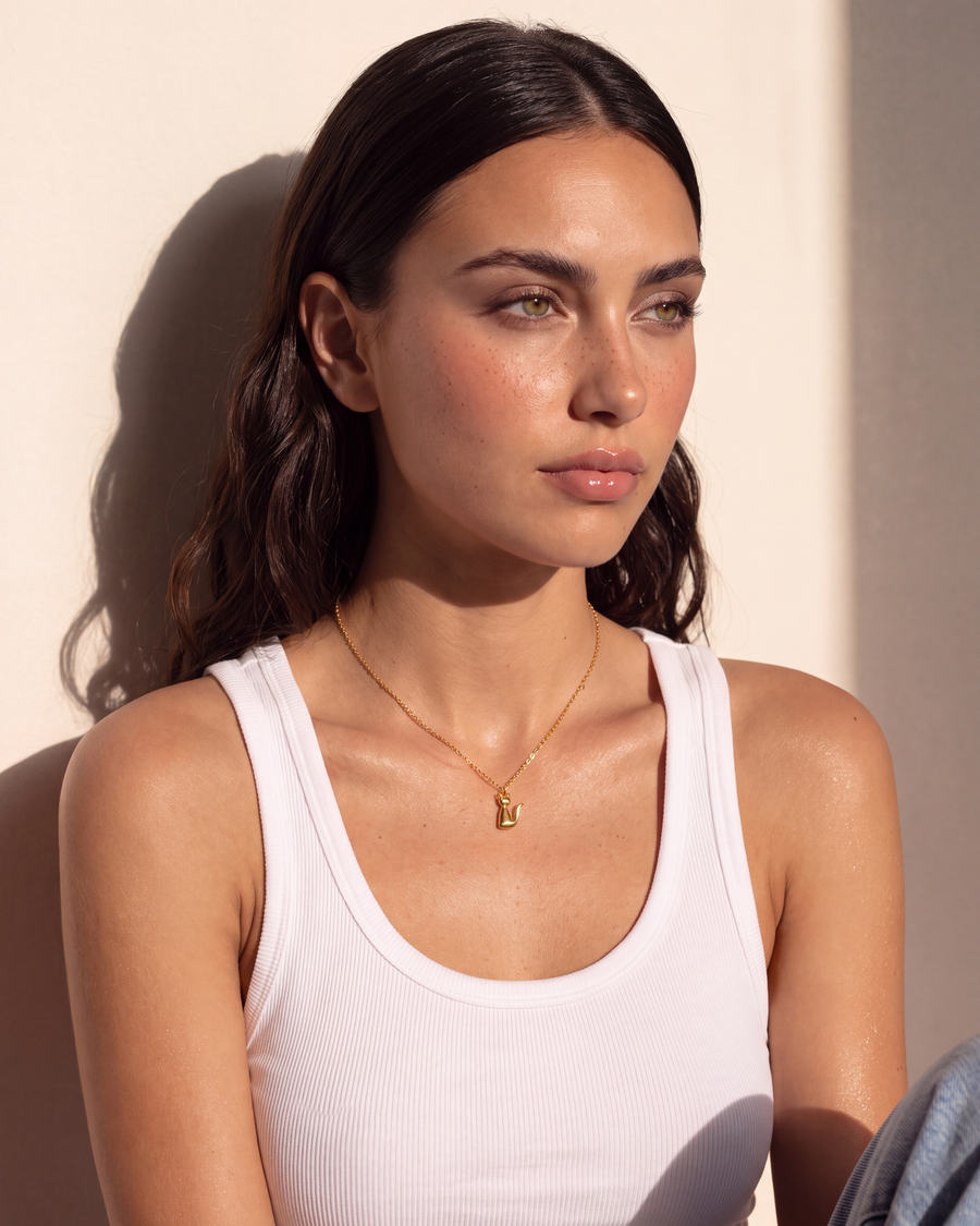 Model seated wearing the Cat Pendant Necklace in afternoon light