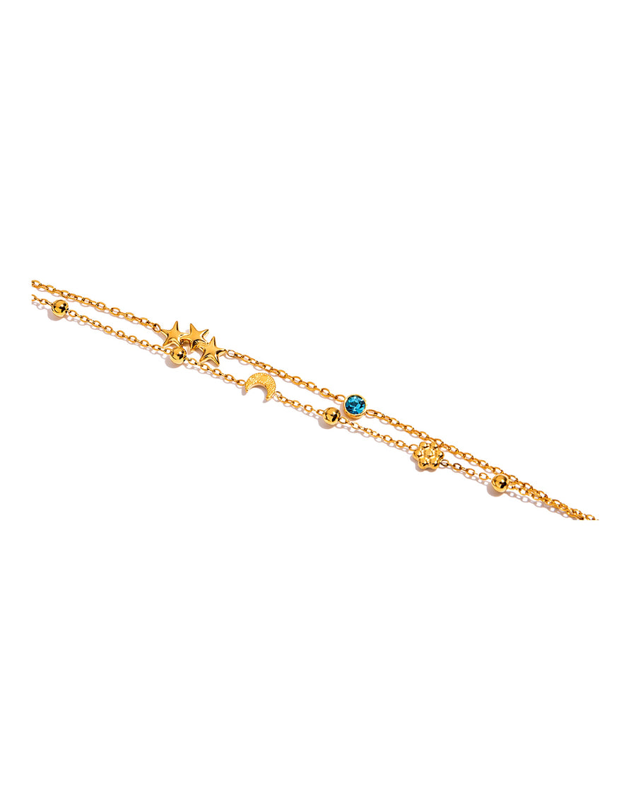 Fine gold double chain bracelet with stars, moon and an aqua crystal on pure white