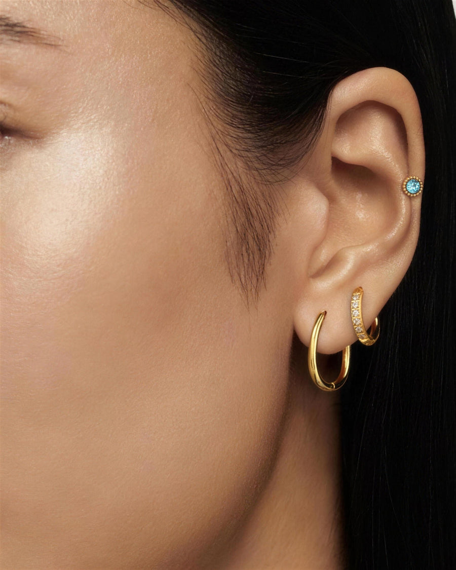 All three pairs worn together in one ear - plain hoop in the lobe, pave hoop above it, aqua stud in the helix