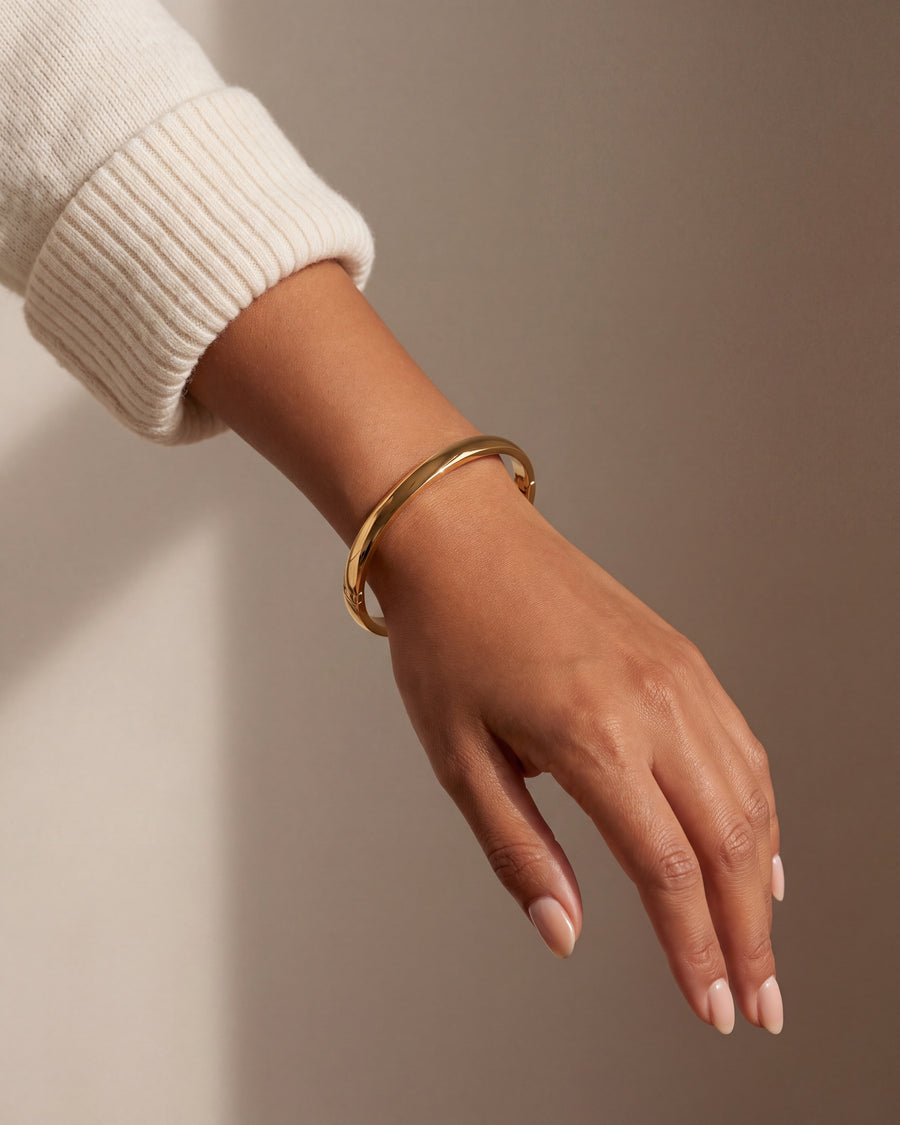 Oval bangle worn on the wrist, showing its narrow everyday width