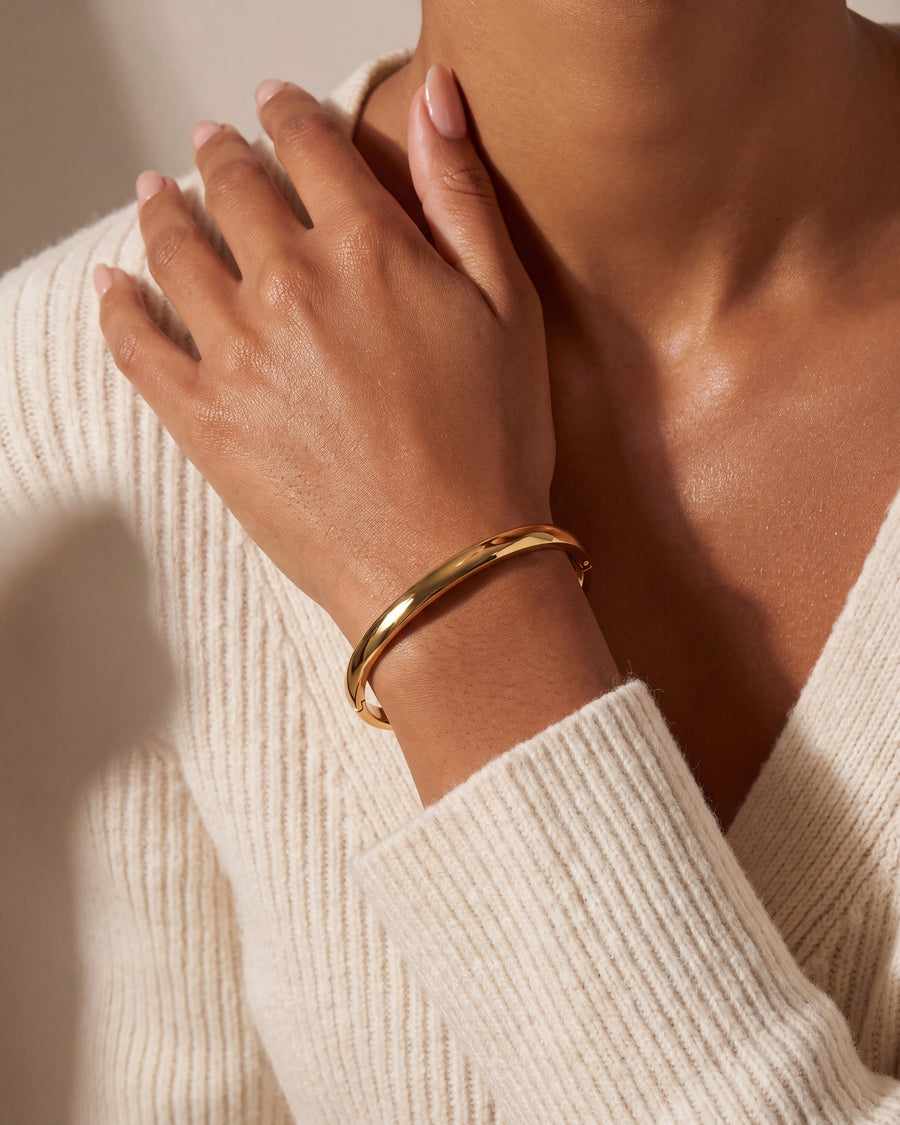 Oval bangle worn with the hand raised to the collarbone