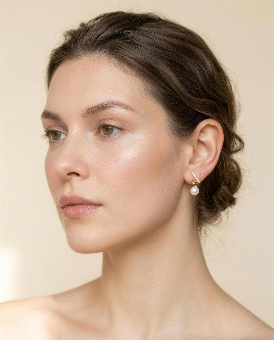 Gold spiral freshwater pearl stud earrings worn on the ear, three-quarter view.