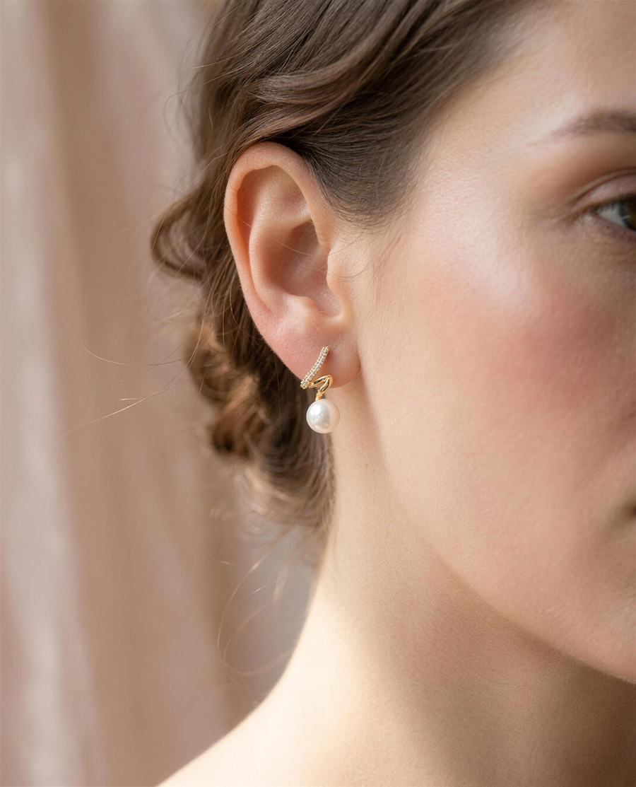 Gold spiral freshwater pearl stud earrings shown close on the ear.