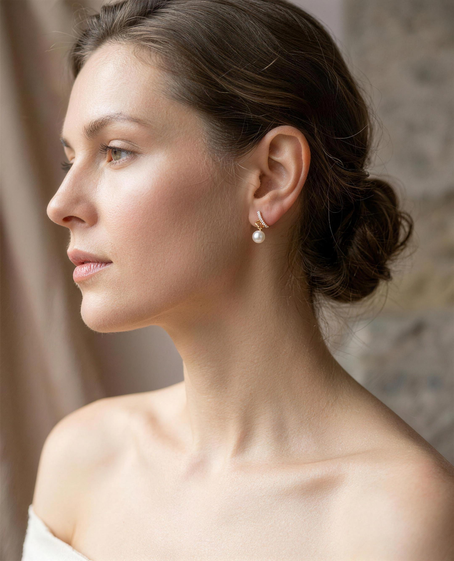 Gold spiral freshwater pearl stud earrings worn on the ear, side view.
