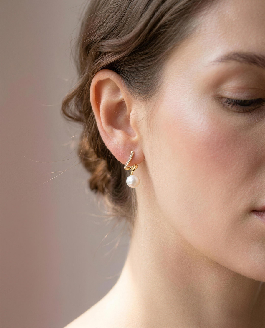 Gold spiral freshwater pearl stud earrings worn on the ear, close portrait.