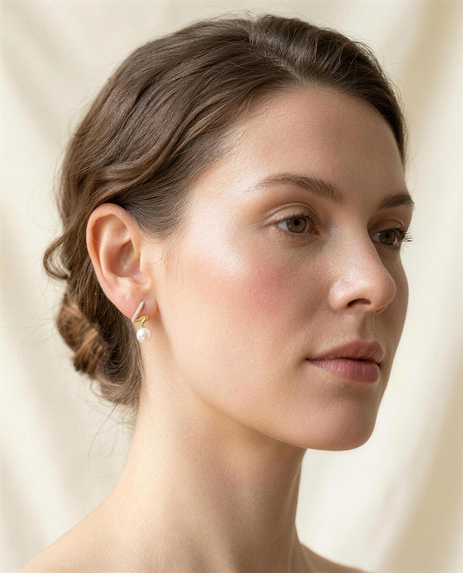 Gold spiral freshwater pearl stud earrings worn on the ear, side profile.