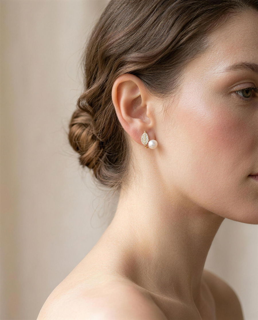 Gold leaf freshwater pearl stud earrings worn on the ear, side view.