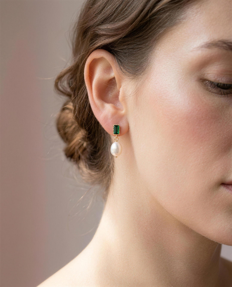 Green stone freshwater pearl drop earrings worn on the ear, close portrait.