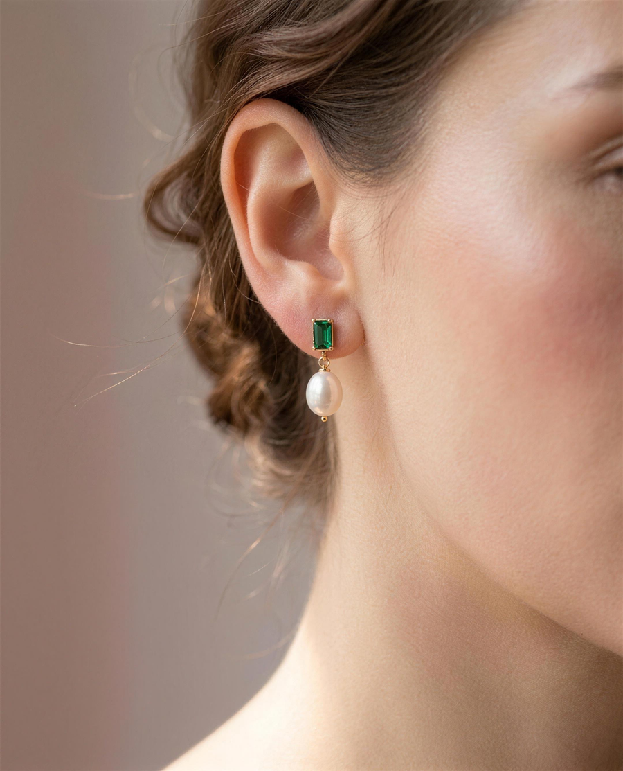 Green stone freshwater pearl drop earrings worn on the ear, head tilted.