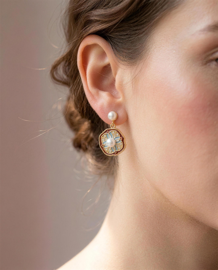 Vintage enamel freshwater pearl drop earrings worn on the ear, head tilted.