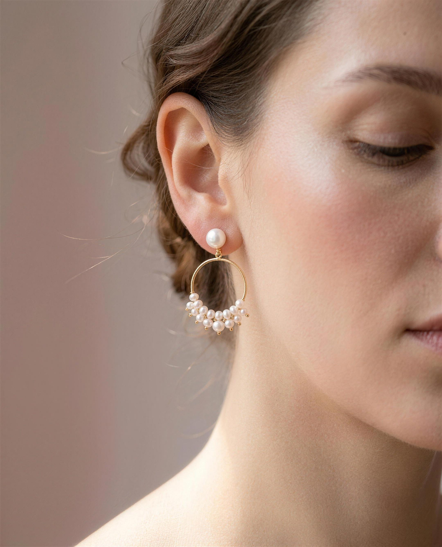 Freshwater pearl cluster hoop earrings worn on the ear, close portrait.