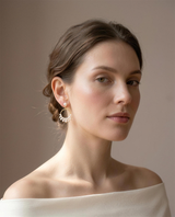 Freshwater pearl cluster hoop earrings worn on the ear, head tilted.