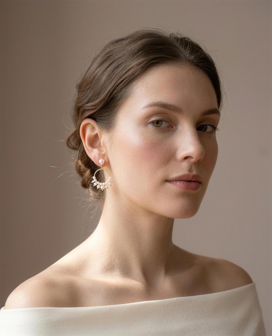 Freshwater pearl cluster hoop earrings worn on the ear, head tilted.