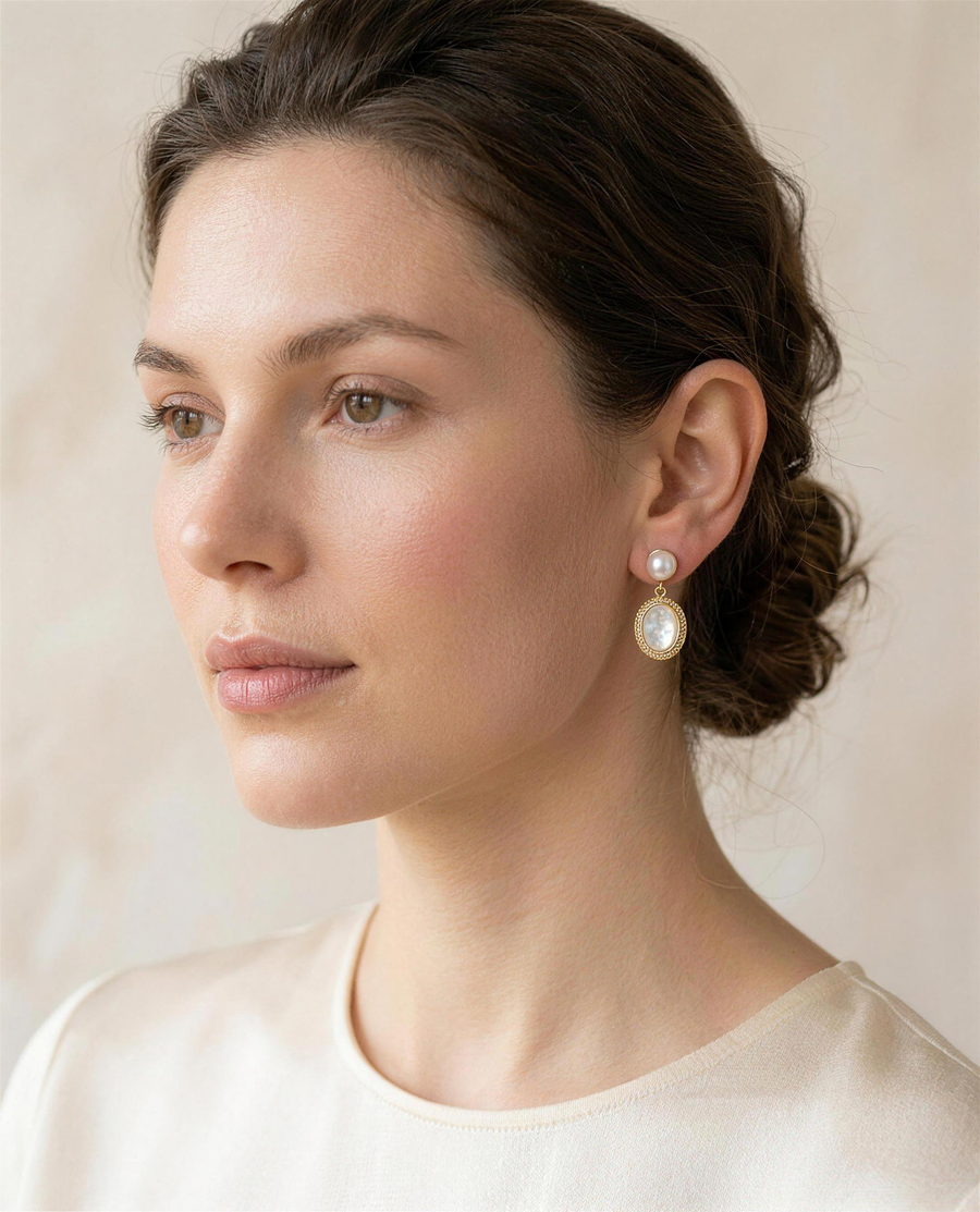 Mother of pearl freshwater drop earrings worn on the ear, three-quarter view.