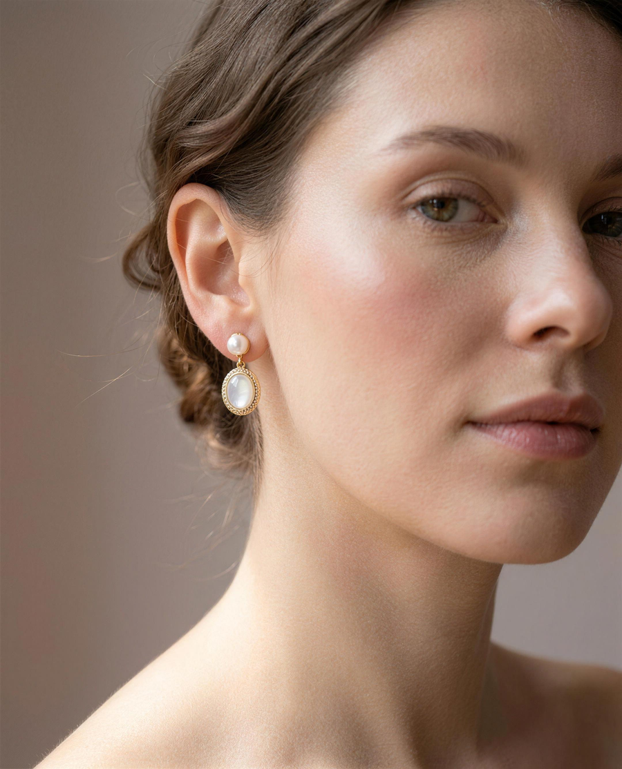 Mother of pearl freshwater drop earrings worn on the ear, head tilted.