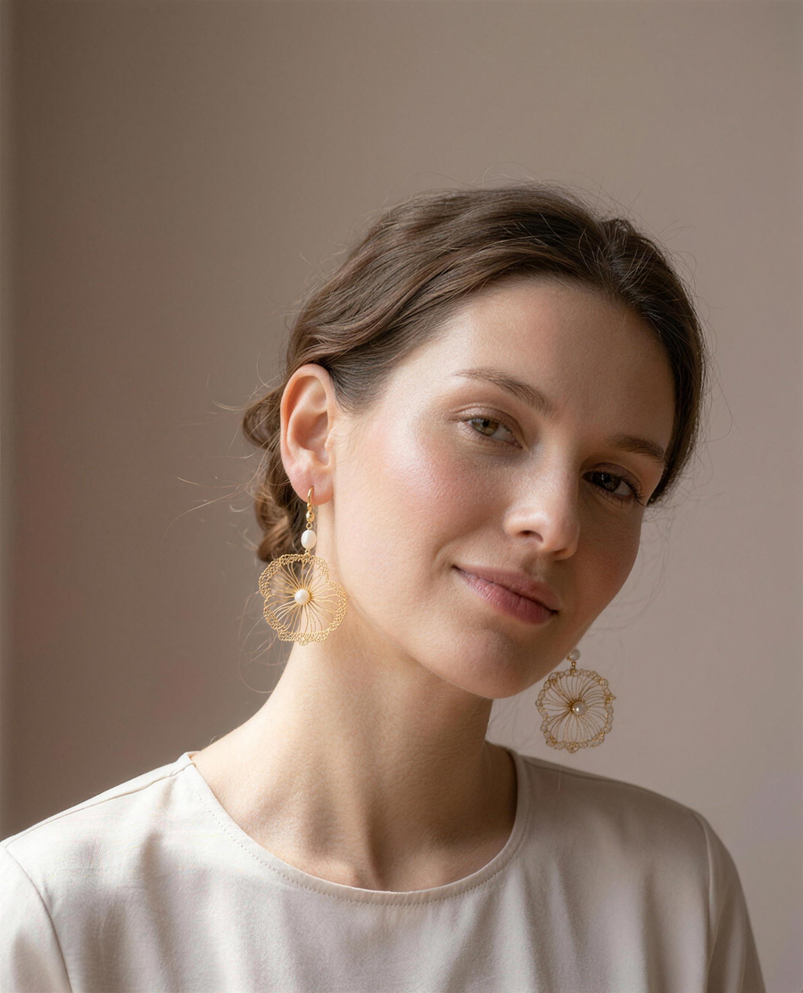 Gold wire freshwater pearl drop earrings worn on the ear, head tilted.