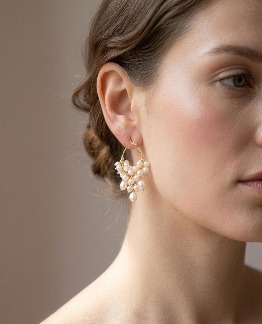 Freshwater pearl cascade hoop earrings worn on the ear, side view.