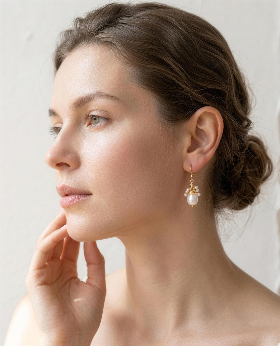 Wire-wrapped freshwater pearl drop earrings worn on the ear, side profile.