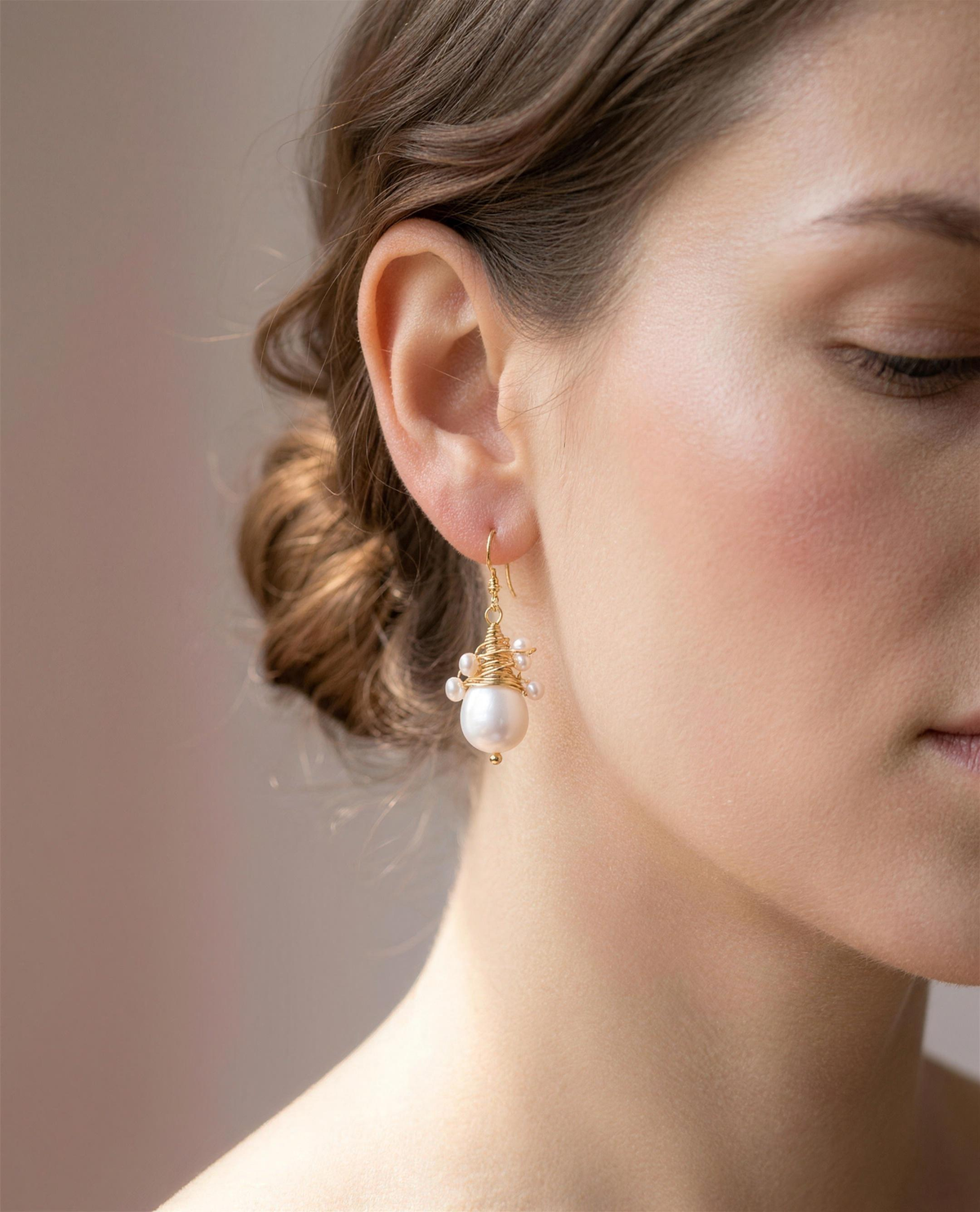 Wire-wrapped freshwater pearl drop earrings shown close on the ear.