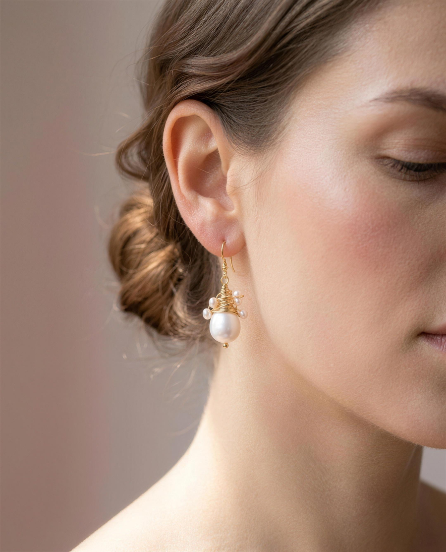 Wire-wrapped freshwater pearl drop earrings shown close on the ear.