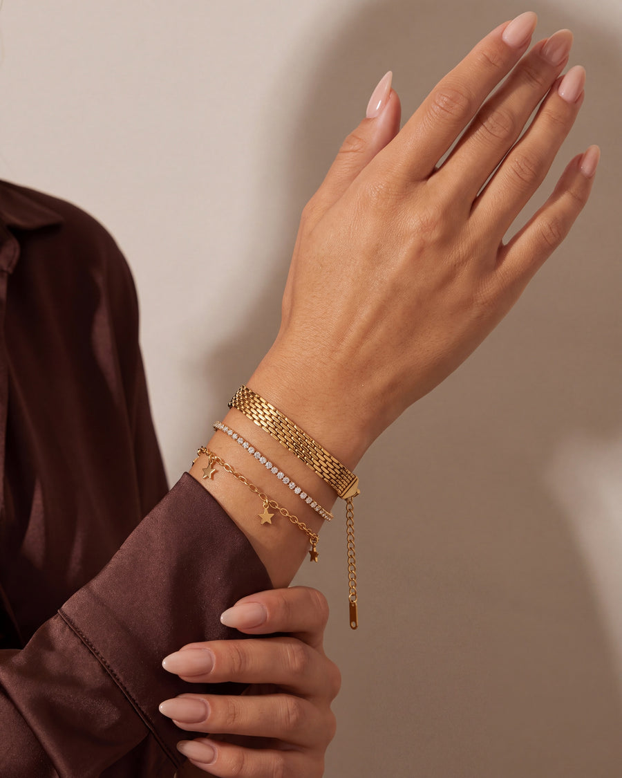 Woven mesh bracelet stacked with fine gold chain bracelets