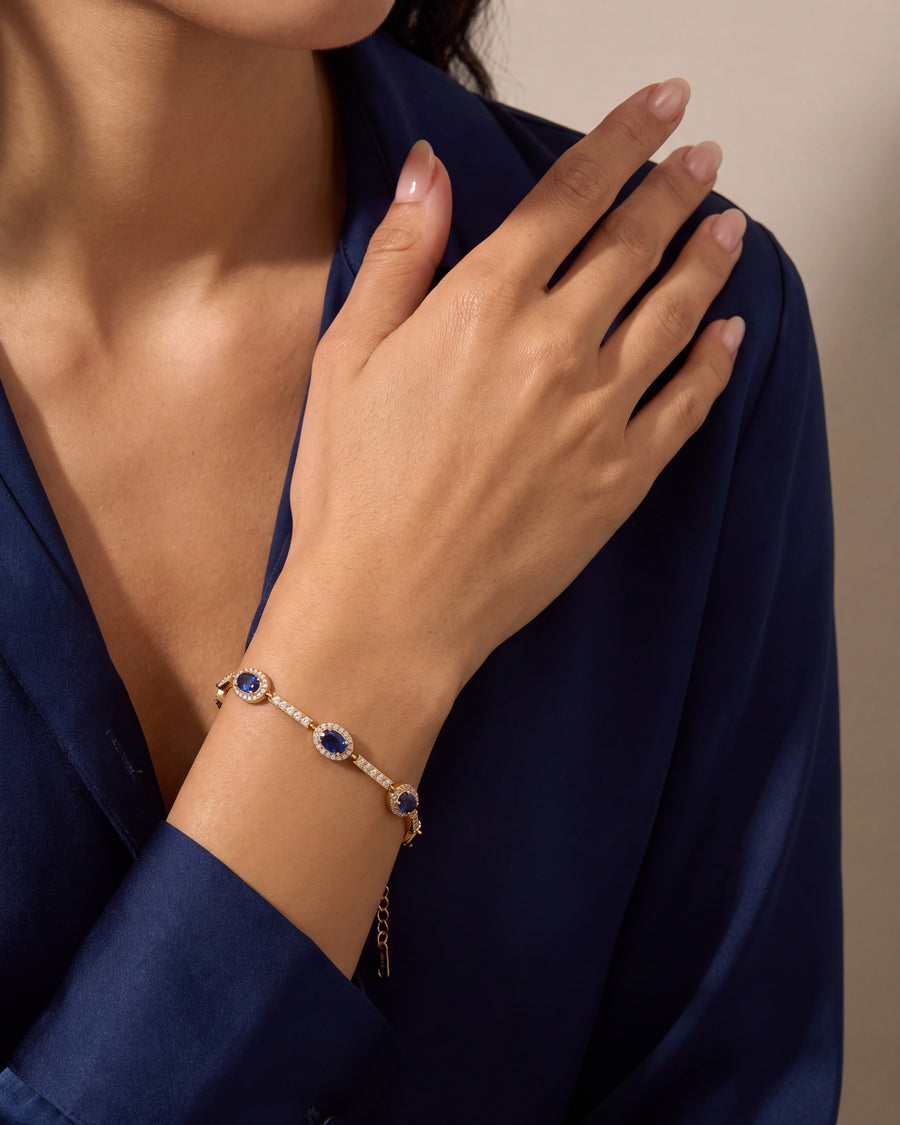 Sapphire halo bracelet worn with the hand raised to the collarbone