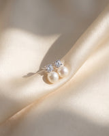 Solitaire and Pearl Studs freshwater pearl earring draped on champagne ivory silk