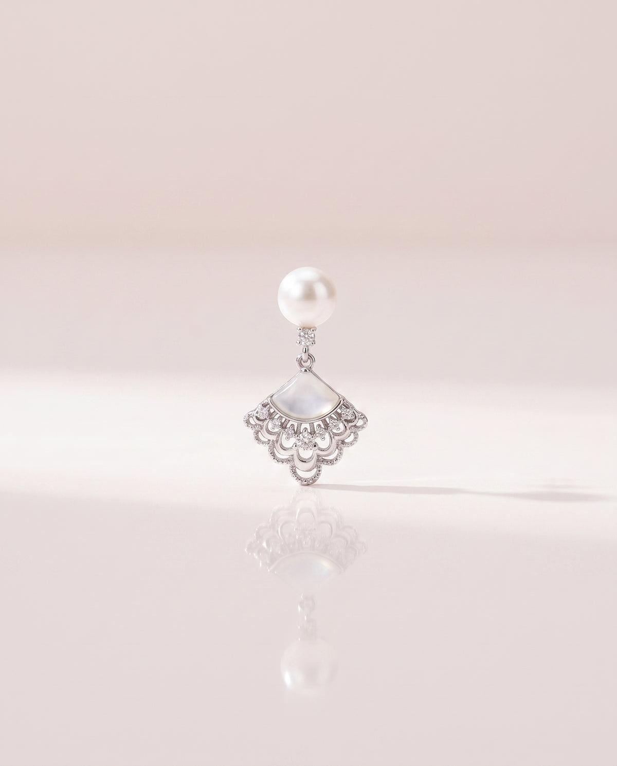 Fan Shell Pearl Drops freshwater pearl earring on a glossy pedestal with soft reflection