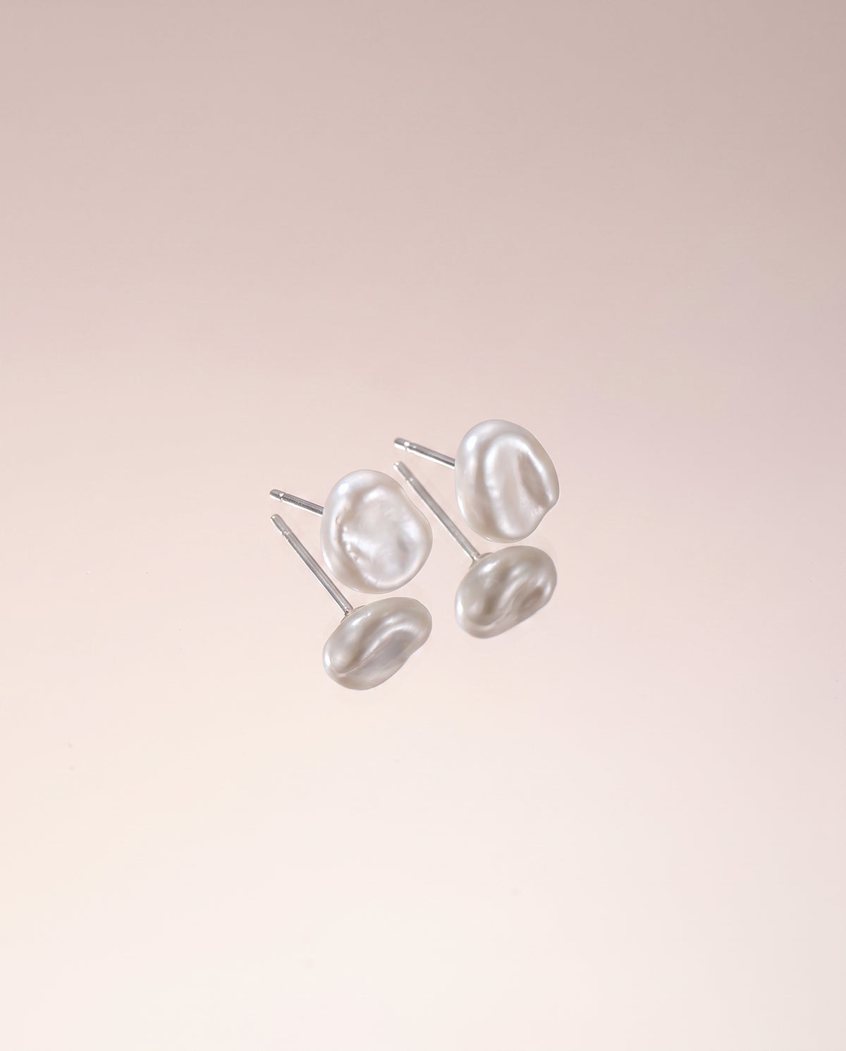 Petite Baroque Pearl Studs freshwater pearl earring on a glossy pedestal