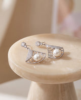 Deco Fan Pearl Drop Earrings on a glossy pedestal