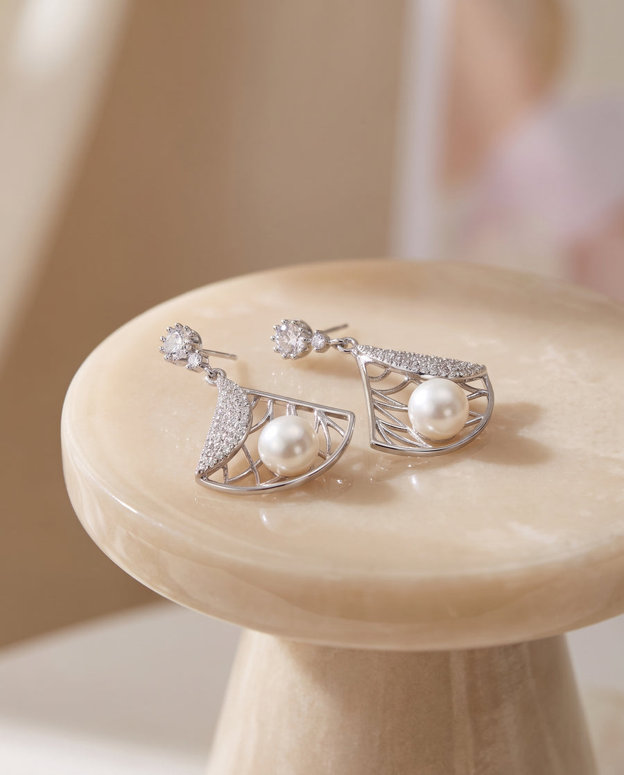 Deco Fan Pearl Drop Earrings on a glossy pedestal